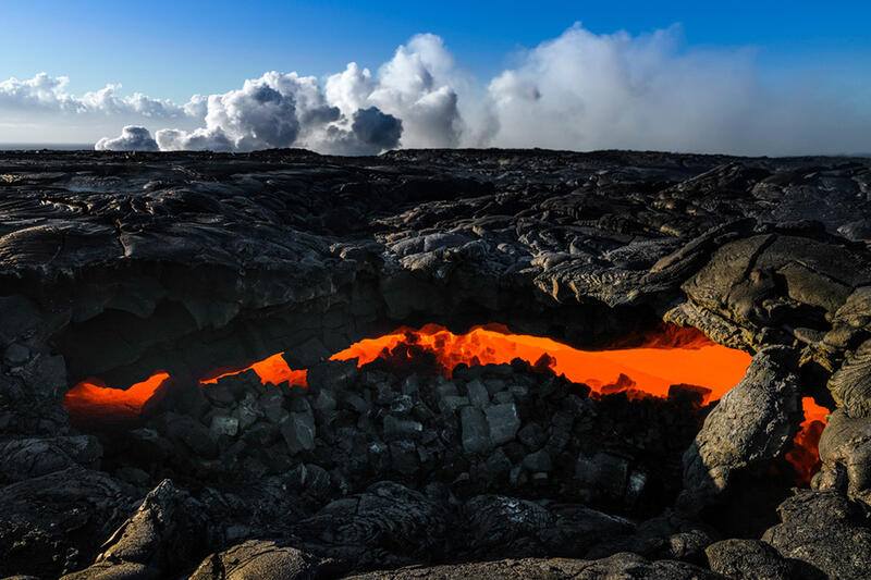 In this image of flowing lava, a lava channel runs boldly under the charred ground. Shop this print & a variety of channels of lava underground images for sale.