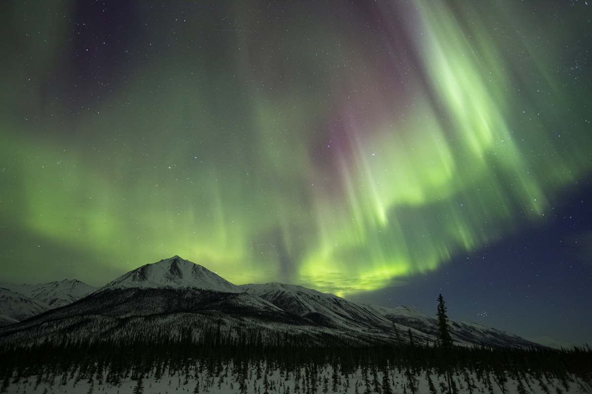 A curtain of Northern Lights dances across the night sky.