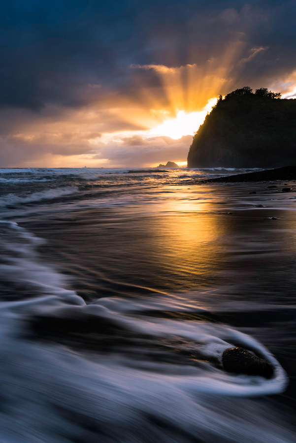 Just as the sun came up the light exploded through the clouds reflecting the warm light across the black sand beach of Pololu...