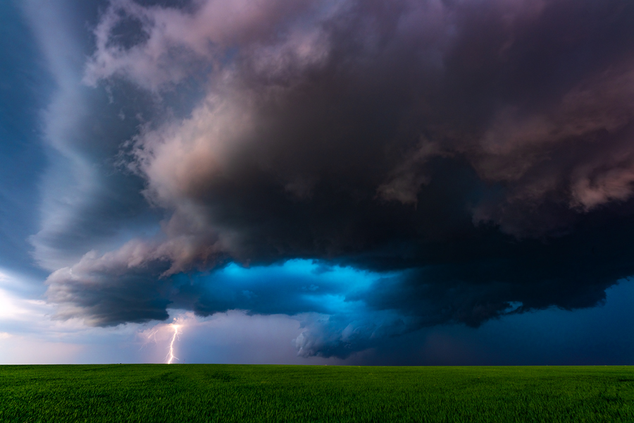 A beautiful structured storm drops countless lightning bolts as the blue hail core glows above.