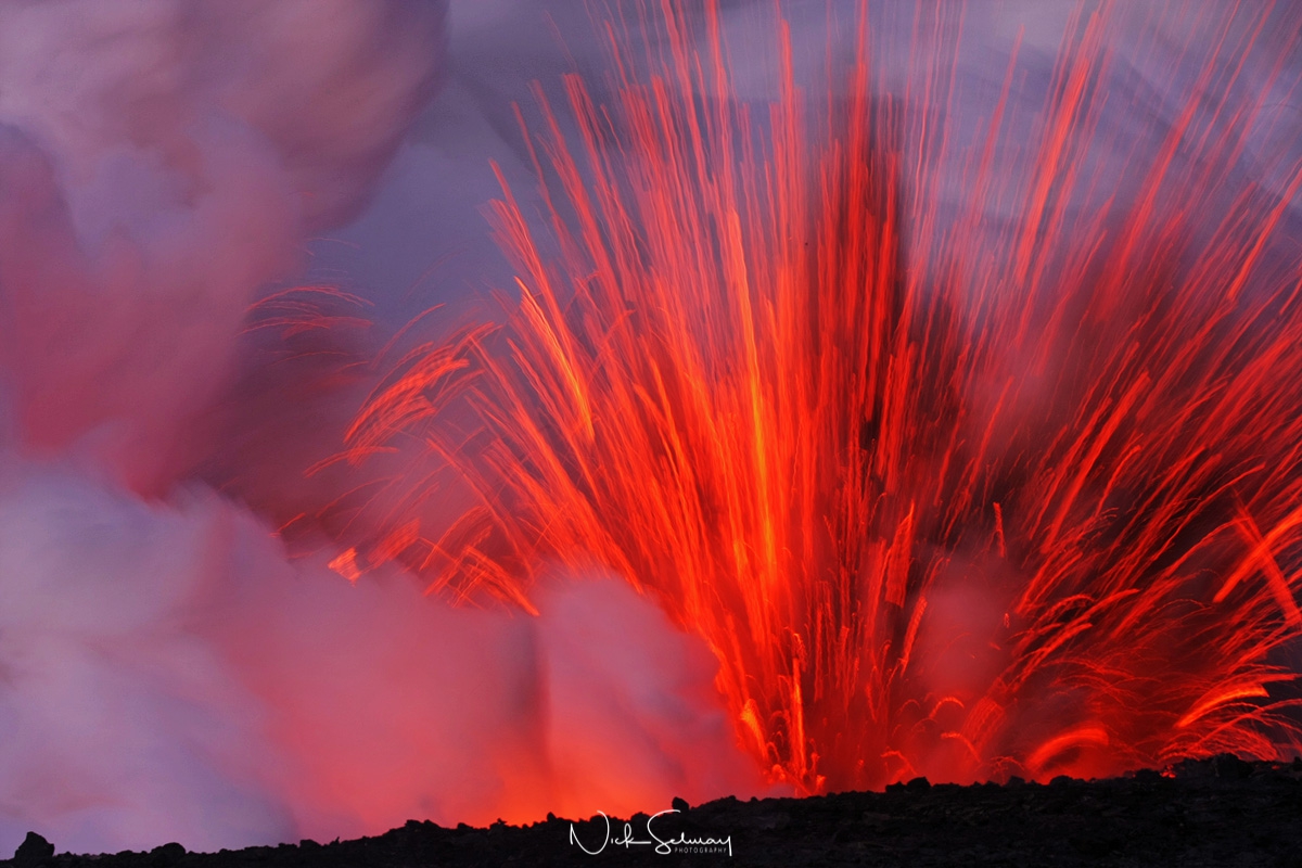 In this beautiful image of lava in Hawaii, lava bursts out of a lava tube along the coast. Shop this print & a variety of beautiful lava photography ​for sale.