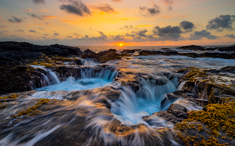 Waves crash against the rugged coast of the Western Side of the Big Island then draining back in to the huge holes making for...