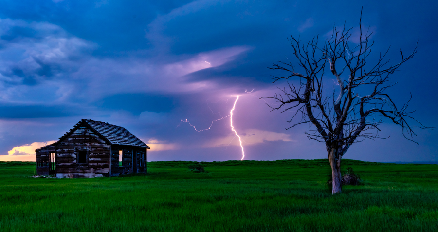 A brilliant lightning bolts strikes in just perfect position between this old structure and a tree making for a compelling composition...